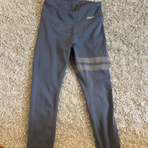 Grå leggings från Stronger - Snygga grå/blå tights från Stronger med hög midja. En liten defekt på prickarna (se andra bilden) men inget man tänker på när man har på sig dom!