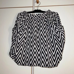 Svartvit kjol - Säljer en luftig svartvit kjol från H&M med coolt zigzag-mönster. Kjolen är tillverkad i ett lätt tyg som ger en avslappnad vibe. Perfekt för dig som gillar grafiska mönster och vill sticka ut lite extra.