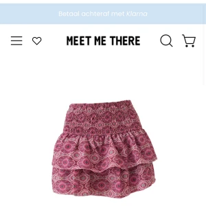 Rosa volangkjol med mönster - Supersöt kort volangkjol i rosa med mönstrat tyg och smockad midja. Kjolen har två lager volanger och ett boho-inspirerat print i rosa och lila toner. Perfekt för dig som gillar färg och vill sticka ut lite extra.