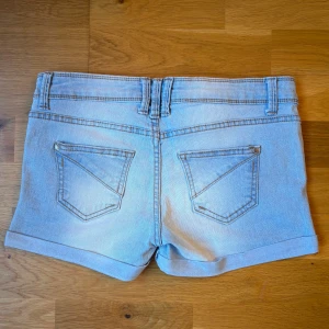 Ljusblå jeansshorts  - Snygga low waist ljusblå jeansshorts från Terranova med klassisk femficksdesign, uppvikta benslut och bälteshällor. Shortsen har en normal passform och stängs med knapp och dragkedja. Super snygg tvätt!! Perfekta för varma dagar och enkel att matcha med allt ☺️Midjemåttet rakt över (liggandes) är ca 37 cm men materialet är relativt stretchigt!! 