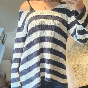 Randig stickad tröja med knappar - Säljer en oversized stickad tröja. Tröjan har rund halsringning och tre snygga knappar på axeln som extra detalj. Jättebra för att dra på sig på stranden. Knappt något tecken på användning <3