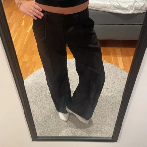 Svarta kostymbyxor från Gina Tricot XS - Säljer ett par svarta kostymbyxor från Gina Tricot i storlek XS. Byxorna har låg midja, raka ben och hällor för bälte. Jätteskönt material och är aldrig använda så de är i bästa skicket. Köparen står för frakten 