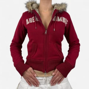 Abercrombie & Fitch Fur Zip Up - Snygg röd hoodiejacka från Abercrombie med fuskpäls på luvan och broderad logga över bröstet. Jackan har dragkedja framtill, ribbade muddar och kängurufickor. Perfekt för dig som vill ha en chill och varm look under höst och vinter. Dragkedjan har bytits ut då den kom trasig, men det är inte så mycket som syns. Storleken är M men sitter som S!💓(Två första bilderna är inte mina)