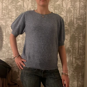 Blå stickad tröja med puffärm VERO MODA - Mysig blå stickad tröja med korta puffärmar och rund halsringning. Tröjan har ribbade muddar vid ärmslut och nederkant, vilket ger en snygg och avslappnad look. Perfekt för dig som gillar en enkel men trendig stil. L men känns som S/M