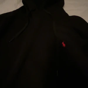 Svart hoodie Polo Ralph Lauren M - Svart hoodie från Polo Ralph Lauren i storlek M. Klassisk modell med huva och snörning, samt den ikoniska röda broderade loggan på bröstet. Passar storlek S och m använd få tal gånger så väldigt ny