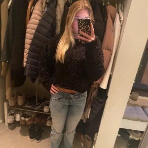 Svart glittrig stickad tröja - Svart stickad tröja med glittriga inslag. Tröjan har lång ärm och en loose fit. Perfekt för dig som vill ha en mysig men ändå snygg look med lite extra glitter.