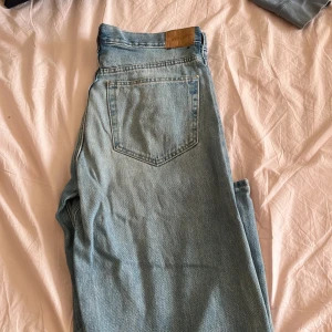 Ljusblå raka jeans från Weekday - Säljer ett par ljusblå jeans från Weekday med klassisk femficksdesign och raka ben. Jeansen har hög midja och är tillverkade i bomullsdenim. Perfekta för en avslappnad och trendig look.