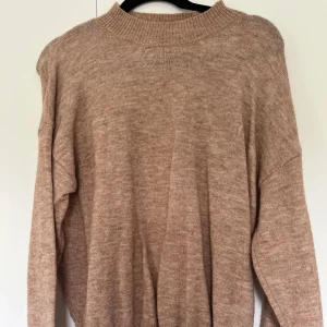 Beige stickad tröja med halvpolo - Mysig beige stickad tröja med hög ribbad krage, nästan halvpolo och långa ärmar. Tröjan har en loose passform! 