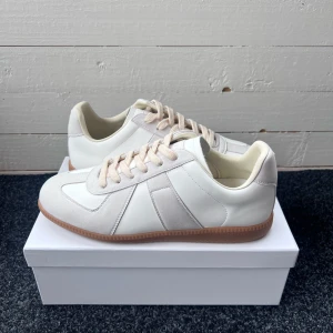 Maison Margiela Gats - Tjena! Säljer nu mina Maison Margiela Gats sneakers i vitt och beige med klassisk retrodesign. Ovandel i skinn och mocka, beige snörning och gummisula. Snygg skor nu till sommaren som passar till allt. Kommer med dustbags och originalkartong. Hör gärna av er! 