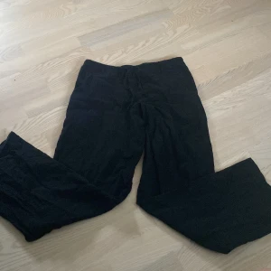 Svarta vida byxor från Gina Tricot - Svarta byxor från Gina Tricot i storlek 158/164. Vida ben och resår i midjan för extra komfort. Tillverkade i mjukt bomullstyg, perfekta för en chill och avslappnad stil.