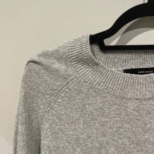 Grå stickad tröja från Vero Moda - Mysig grå stickad tröja från Vero Moda med rund halsringning och ribbade muddar. Perfekt för lager-på-lager och enkel att matcha med jeans eller kjol. Långärmad och i klassisk, rak passform.