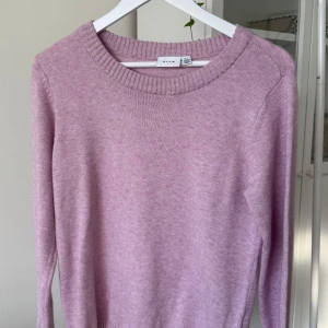 Rosa stickad tröja från Vila - Superfin rosa stickad tröja från Vila med rund halsringning och långa ärmar. Tröjan har en ribbad kant vid halsen och är perfekt för dig som gillar en enkel men snygg stil. Passar till både jeans och kjol!