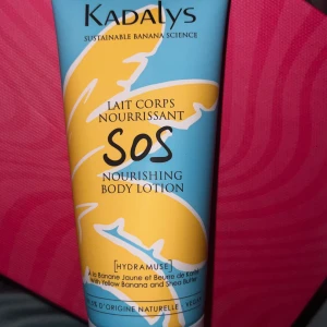 Kadalys SOS Nourishing Body Lotion - Kadalys SOS Nourishing Body Lotion med banan och sheasmör. Kommer i en blå och gul tub med tropisk design. Vegansk och naturlig formula som återfuktar huden på djupet. Perfekt för dig som vill ha en fräsch och mjuk känsla.