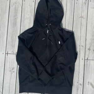 Svart hoodie från Polo Ralph Lauren - Svart zip hoodie från Polo Ralph Lauren med klassisk broderad logga på bröstet. Är i superskick och tvättar den såklart innan ja skickar och då försvinner dom minimala fläckarna som syns på bild 1. Storlek M, hör av er vid funderingar!