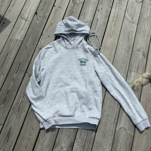 Grå hoodie - Grå hoodie med grönt tryck i storlek XS. Jag har tagit ut snöret men det finns kvar och går att stoppa in igen💓