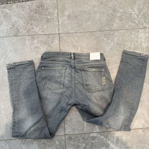 Grå slim jeans från Jack & Jones - Snygga grå jeans från Jack & Jones i slim fit-modell. Jeansen har klassisk femficksdesign, bälteshällor och subtila slitningar för en cool look. Tillverkade i mjukt denimtyg med stretch för extra komfort. Perfekta till sneakers och hoodie. Dm för frågor🤝🙌