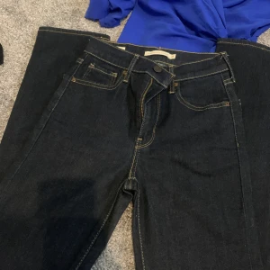 Levi's 724 High Rise Straight jeans - Mörkblå Levi's 724 High Rise Straight jeans med klassisk femficksdesign och kontrastsömmar. Hög midja och raka ben ger en clean och tidlös look. Tillverkade i slitstarkt denim med snygg passform som funkar till allt.