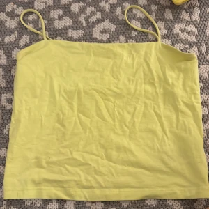 Gul linnetopp från Gina Tricot - Snygg ljusgul linnetopp från Gina Tricot i storlek M. Toppen har tunna axelband och ärmlös design, perfekt för varma dagar. Tillverkad i mjuk bomull som känns skön mot huden. Enkel och stilren modell som är lätt att matcha med olika outfits.