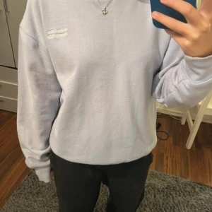 Ljuslila sweatshirt - • supermjuk ljuslila sweatshirt med vit text på bröstet. • klassisk rund halsringning, ribbade muddar och avslappnad passform. • perfekt för chill dagar och enkel att matcha med jeans eller mjukisbyxor.