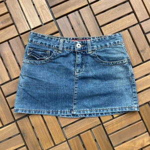 Blå jeanskjol med fickor - Snygg blå jeanskjol i klassisk modell med fem fickor, bälteshällor och kontrastsömmar. Kjolen är kort och har knapp- och dragkedjestängning framtill samt dekorativa bakfickor med knappar. Perfekt för en chill och trendig look. Mått finns på bilderna 💗