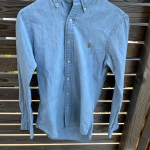 Ralph Lauren skjorta ljusblå - Säljer denna snygga Ralph Lauren skjorta! Perfekt skick✅ Inga defekter✅ Passar runt 165-175cm✅ Perfekt till sommaren☀️ Hör av er vid frågor och funderingar!🤝