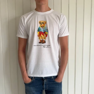 Ralph Lauren Tshirt - En riktig snygg vit Ralph Lauren T-shirt med Polo bear tryck. Skick 10/10 inga defekter eller liknande. Storlek M men passar även S. Hör gärna av er vid frågor och funderingar!🤗