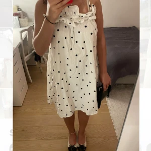 Vit prickig kortklänning - Supersöt vit kortklänning från H&M med svarta prickar och tunna axelband. Klänningen har volangdetaljer och en rak passform. Det står att den är S men skulle säga att den är ganska så stor så snarare M. Den är typ i nyskick. Perfekt för sommaren och så himla gullig!!