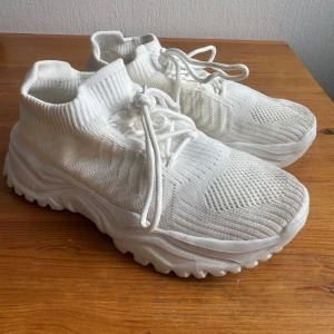 Vita Sneakers, storlek 38 - Ett par vita sneakers med snören och tjock sula. Perfekt för en avslappnad och bekväm stil.