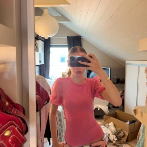 Rosa mesh topp med puffärmar - Säljer en rosa mesh topp med korta puffärmar och rund halsringning. Toppen är tight och har en lätt transparent look som ger en trendig vibe. Perfekt att styla med jeans eller kjol för en cool och feminin outfit. Lappen är bortklippt men den jag vet att jag har köpt den från Zara