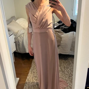 HELT OANVÄND Ljusrosa balklänning med omlott överdel - Elegant ljusrosa långklänning med omlottlagd överdel och breda axelband. Klänningen har markerad midja och faller mjukt ner till golvet. Perfekt för bal eller fest. Snygg och stilren design. Från Asos