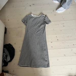 Svartvit randig klänning från H&M - Säljer en svartvit randig klänning från H&M. Klänningen har korta ärmar, rund halsringning och raka svarta och vita ränder. Modellen är enkel och rak, perfekt för en avslappnad stil.