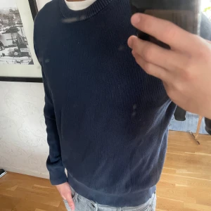 Mörkblå stickad tröja  - Säljer en mörkblå stickad tröja från East West i storlek L, men den sitter lätt som storlek M. Fortfarande i bra skick, enkel och stilren design som passar till det mesta.