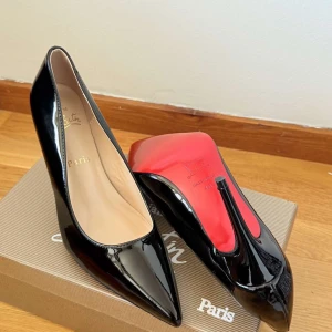 Svarta lackpumps från Christian Louboutin - Säljer ett par klassiska svarta pumps i lack från Christian Louboutin med ikonisk röd sula och spetsig tå. Skorna har hög klack och elegant form, perfekta för att lyfta vilken outfit som helst.