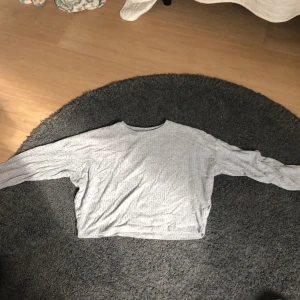 Ljusgrå ribbad tröja från H&M - Säljer en ljusgrå ribbad tröja från H&M i storlek 158/164. Tröjan har lång ärm och en enkel, rak passform. Perfekt för dig som gillar en basic och stilren look.