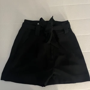Svarta shorts med knytning - Snygga och stilrena svarta shorts med knytning i midjan ❤️‍🔥 typ samma material som kostymbyxor. Använda fåtal gånger, jättefint skick. Skriv meddelande vid frågor/fler bilder 🤩