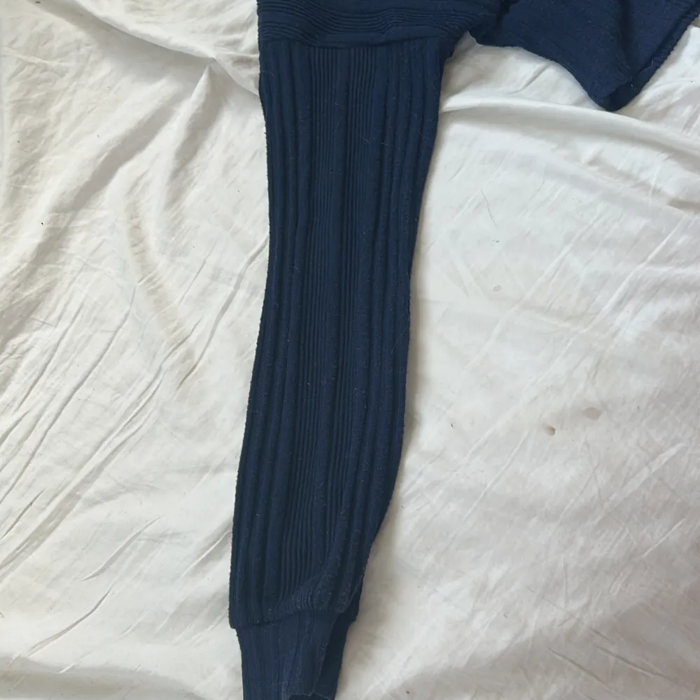 Säljer en mörkblå croppad tröja från NA-KD med ribbad struktur. Tröjan har långa ärmar och en liten v-ringning vid halsen. Perfekt till jeans eller kjol för en avslappnad look.. Neuletakit & Villapaidat.