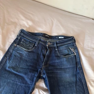 Mörkblå jeansbyxor från Replay - Säljer ett par mörkblå jeans från Replay med klassisk femficksdesign och snygga slitningar. Byxorna har raka ben och normal passform, med läderpatch bak i midjan och diskreta Replay-detaljer på fickorna. Och byxorna är i perfekt skick och skulle rekommenderas! Storleken är 31 i midjan och längden 34. Pris 350 kr