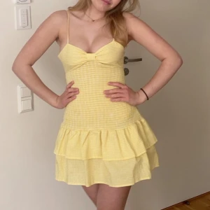 Gul rutig volangklänning med rosett - Söt gul kortklänning med rutigt mönster och volangkjol. Klänningen har smala axelband, söt rosett i ryggen och omlottkänsla baktill. 💛💛💛