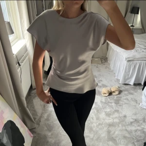 Grå kortärmad topp - Säljer en stilren grå topp med korta ärmar. Toppen har en mjuk och glansig yta som ger en elegant touch. Perfekt för en chic och avslappnad look. Priset går att diskutera❤️
