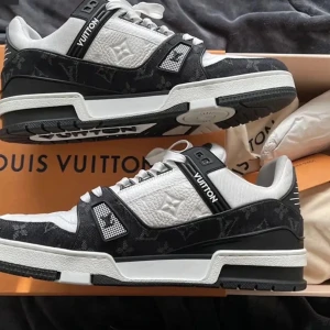 Sneakers i svart och vitt - Säljer ett par nya och snygga sneakers i svart och vitt med monogramdetaljer och tydlig logga på sulan. Skorna har snörning, rund tå och är tillverkade i en mix av skinn och syntetmaterial. Perfekta för dig som gillar exklusiva och stilrena sneakers.