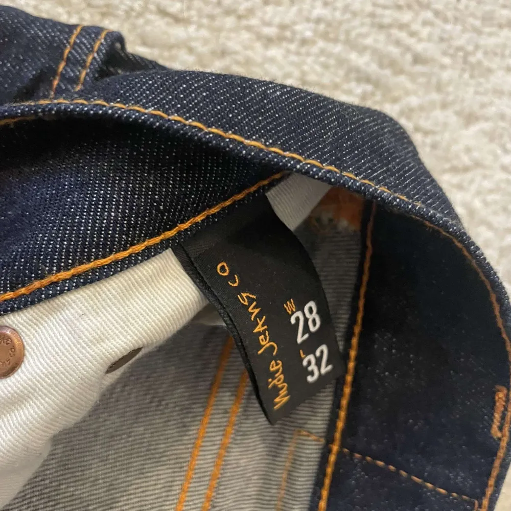 Snygga mörkblå jeans från Nudie Jeans med klassisk femficksdesign och kontrasterande sömmar. Perfekta för en stilren look. OBS DOM HAR KRYMP REJÄLT MYCKET SÅ DOM ÄR STL 15/17 ish. Farkut & Housut.