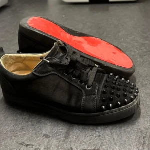 Loubs - Säljer ett par svarta sneakers från Christian Louboutin med matta nitar på tån och klassisk röd sula. Dom är väl använda, skulle säga att dom är i acceptabelt skick. 