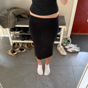 Svart ribbad lång kjol från VILA - Säljer en svart ribbad lång kjol som är köpt på VILA. Kjolen har en tight passform och är tillverkad i ett stretchigt material som sitter snyggt på kroppen. Stolek XS. 