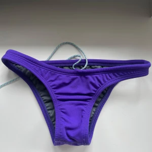Lila bikiniunderdel från Jolyn - Lila bikiniunderdel från Jolyn med justerbar snörning i midjan. Storlek small. Bra skick. Modell: Brazil bikini underdel. 