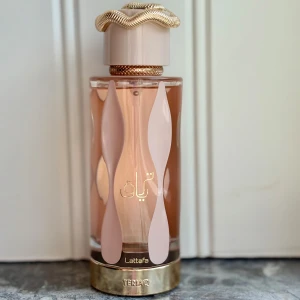 Teriaq Eau de Parfum från Lattafa - Upptäck Teriaq, en unisexparfym från Lattafa med en söt och karamellaktig doft. Doften kombinerar noter av karamell, bittermandel och aprikos med en hjärtnot av honung och ros, och en bas av läder och vanilj. 100 ml, enbart testad, kommer i originalkartongen.