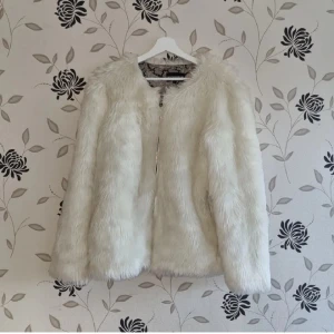 Vit fuskpälsjacka, Rock and Blue, Strl: M/38,  - Säljer en stilren vit pälsjacka med långärmad design och ett snyggt mönstrat foder. Perfekt för att hålla sig varm och trendig under kyliga dagar. Jackan har en enkel stängning framtill. Rock and Blue.