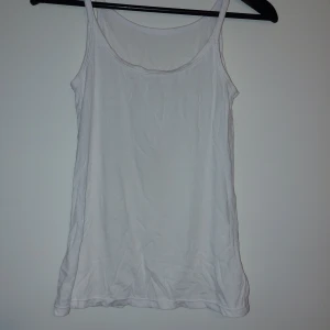 Vit linnetopp - En enkel och klassisk vit linnetopp med smala axelband och rund halsringning. Perfekt att bära under andra plagg eller som den är under varma dagar.Endast tvättad.