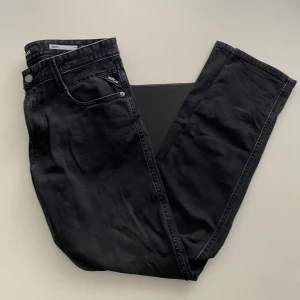 Svarta Replay Anbass jeans - Säljer ett par svarta Replay Anbass jeans med slim fit. Klassisk femficksmodell med Replay-logga på bakfickan och metallknapp framtill. Snygga svarta sömmar och diskret tvättad look. Perfekta för dig som gillar stilrena jeans med modern passform. W32 L32