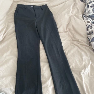 Mörkgrå kostymbyxor från Bik Bok - Säljer ett par mörkgrå kostymbyxor från Bik Bok i klassisk modell. Byxorna har raka ben, hällor för bälte och diskreta fickor bak. Sitter tight vid rumpa och lår. Snäppet vidare från knä och nedåt. Älskar dem men för små. Köpta i vintras på bikbok. Använda en gång. 