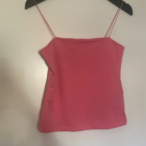 Rosa linnetopp från Amisu - Säljer en enkel och stilren rosa linnetopp från Amisu. Toppen har tunna axelband och rak halsringning, perfekt för varma dagar eller som layering-plagg. Supermjuk och lätt att matcha med olika outfits!